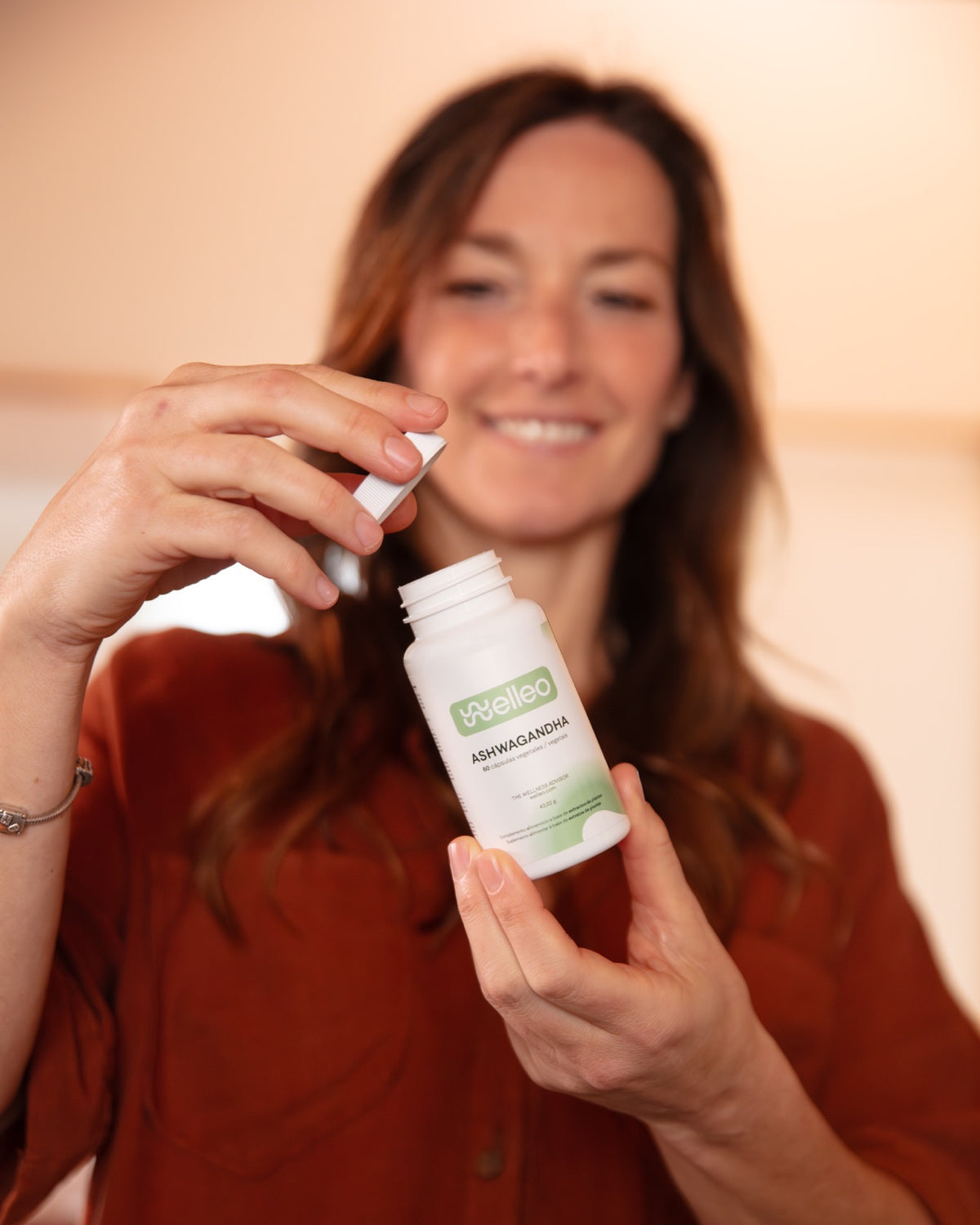 A woman opening a bottle of welleo Ashwagandha