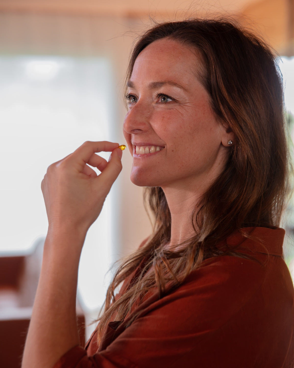 A smiling woman about to take a softgel